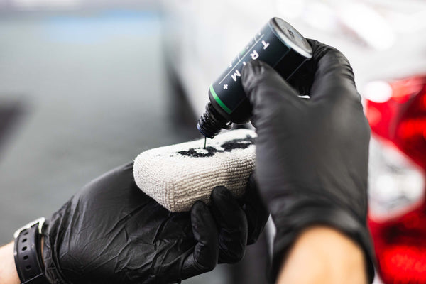 Armour Detail Supply Trim Plus 50ml bottle being poured onto an applicator.