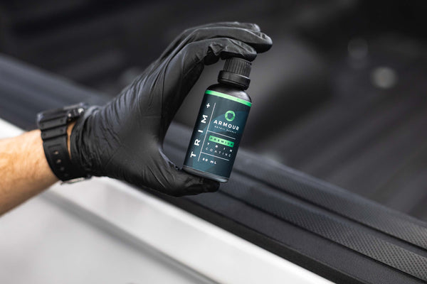 Armour Detail Supply Trim Plus 50ml bottle being held in a persons hand/