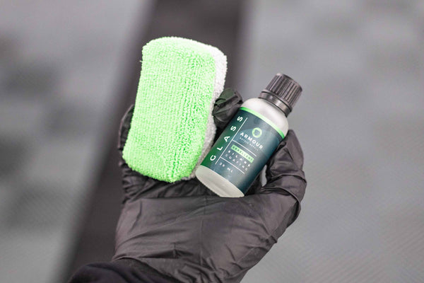 Armour Detail Supply Glass Coating 30 ml bottle and Sponge being held in a persons gloved hand.