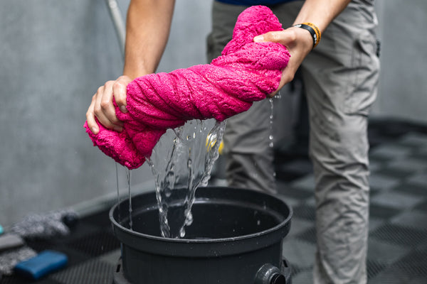 A person ringing out water from an Armour Detail Supply M22.