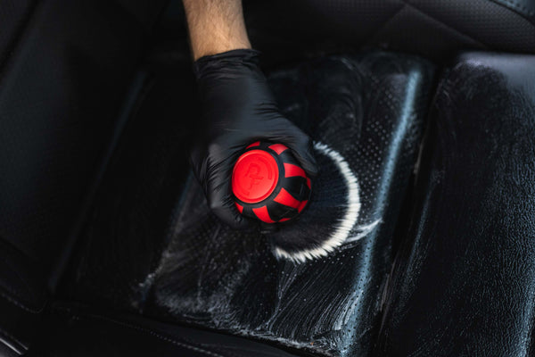 Person cleaning car seat interior with a Detail Factory Curveball Red.