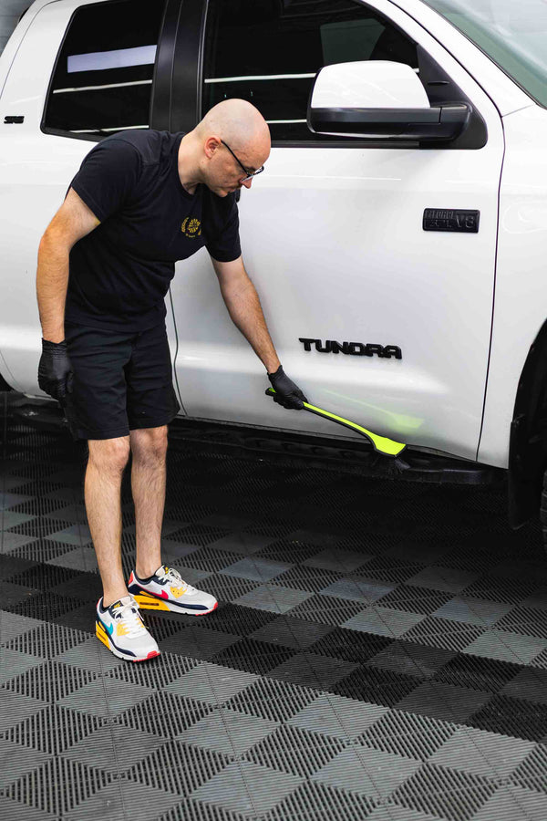 Person cleaning a white Toyota Tundra truck with a Detail Fender Well Brush ectoplasm.
