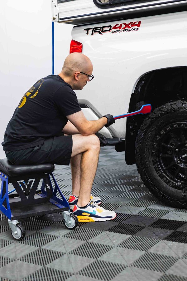 Person cleaning a white Toyota Tundra truck with a Detail Fender Well Brush underglow.