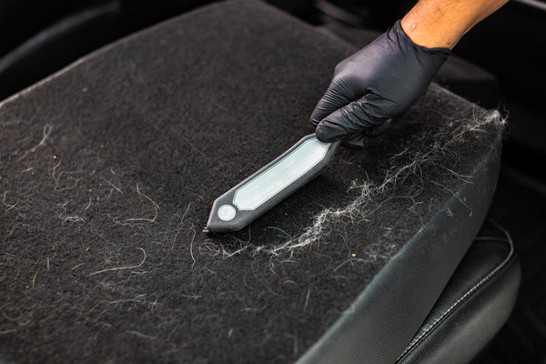 A hand cleaning the back of a car with the Detail Factory Pet Hair Brush.