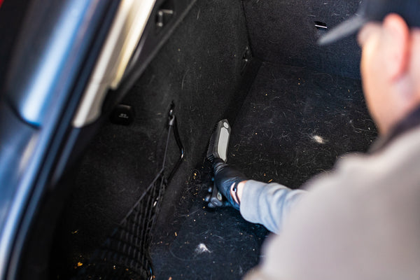 A person cleaning the back of a car with the Detail Factory Pet Hair Brush.