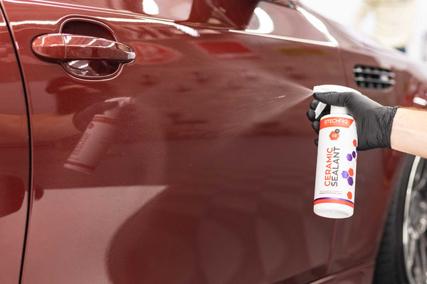 Gtechniq C2V3 being sprayed onto a red car door panel.