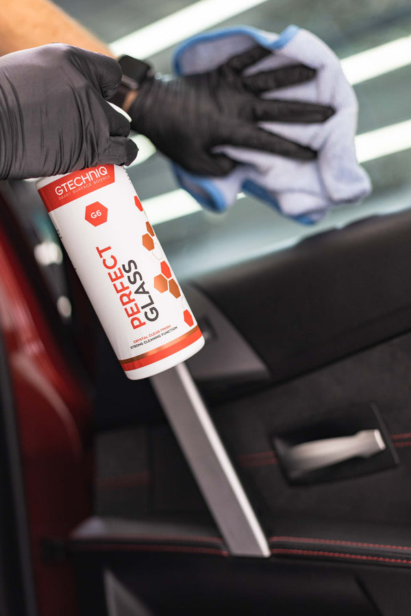 Gtechniq G6 Perfect Glass spraying and being wiped off with a towel from car window.