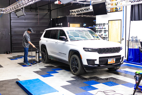A person cleaning a Jeep Cherokee with an IK Sprayer.
