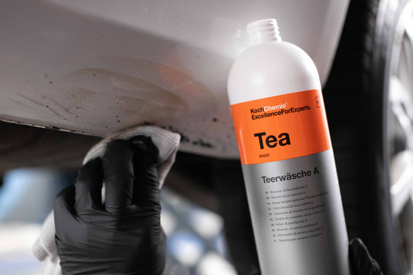A person scrubbing grime off the bottom of a car cab with a towel dipped in Koch Chemie Tea.