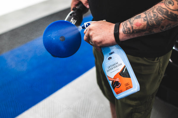 A person spraying Optimum Hyper Polish to a blue polish pad.