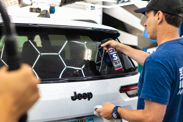 P&S Triple S being sprayed on the back windshield of a jeep car.