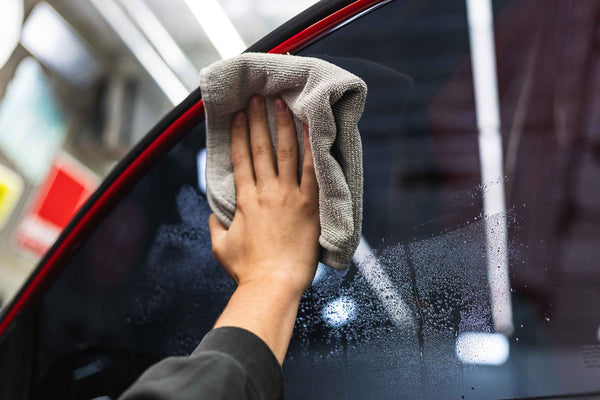 Person cleaning a car window with a grey FTW