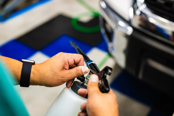 A person adjusting the settings of an Ultra Air Engine Blaster with a blurry background of a car.