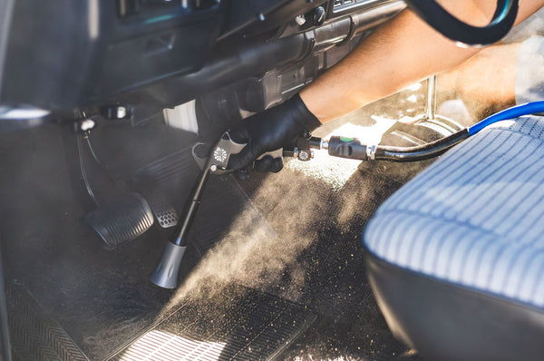 A closeup of a person using the Ultra Air Blaster to clean the floor of a Toyota Land Cruiser.