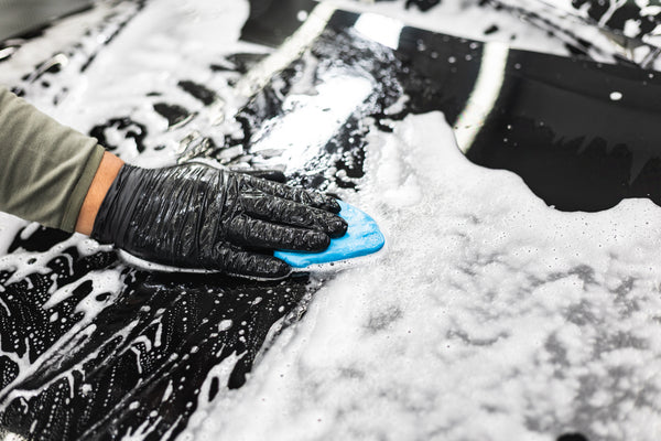 The Rag Company Ultra Clay Bar being used on a soapy black vehicle.