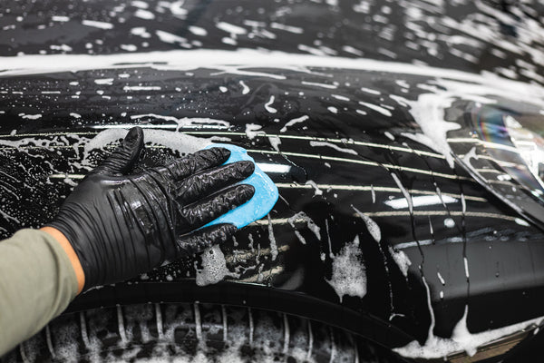 The Rag Company Ultra Clay Bar being used on a soapy black vehicle.