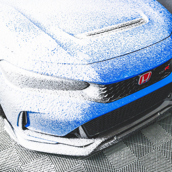 A blue car with soap on it from using a TRC Ultra H2O Foam Cannon to spray soap onto it.