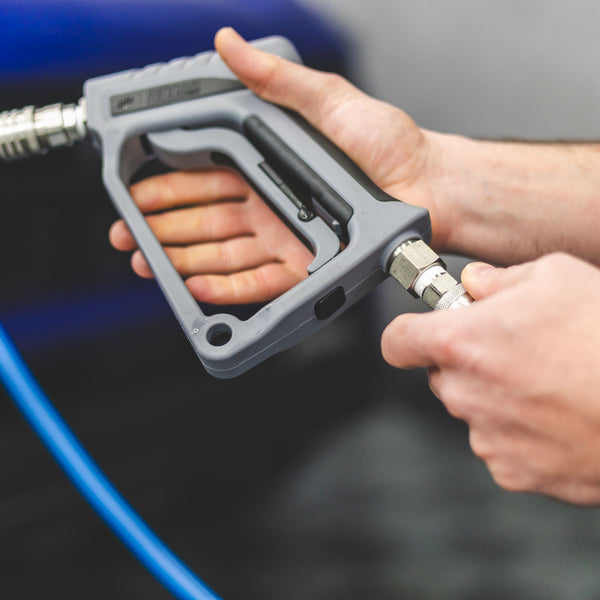 A person connecting a TRC Ultra H2O Spray Gun to a pressure washer hose.