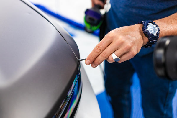 A person using a Yellotools Lacy Tip to lay vinyl in the crack of a car.