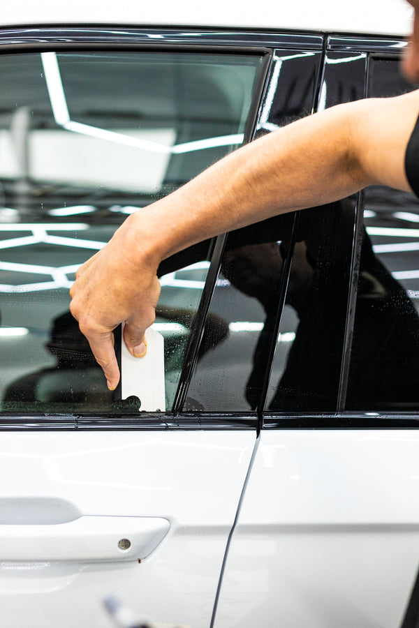 A person using a Yellotools YelloFlex Shape on a car window.