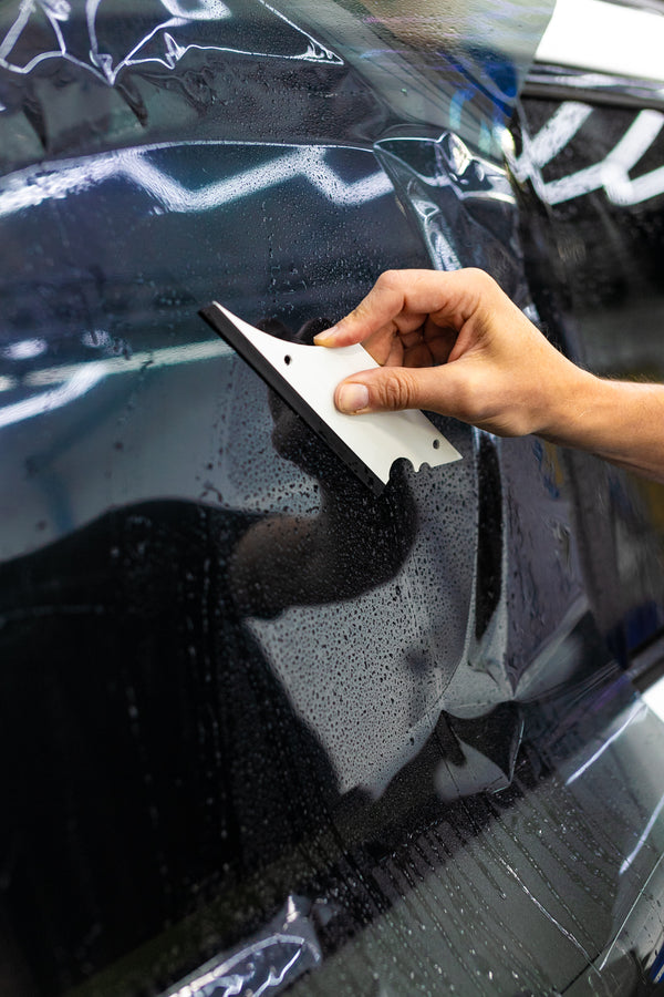A person using a Yellotools YelloFlex Shape on a black car.