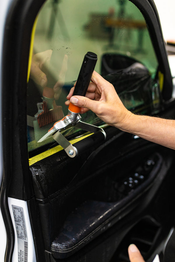 A person using the Yellotools Wetmaxx on a car window.