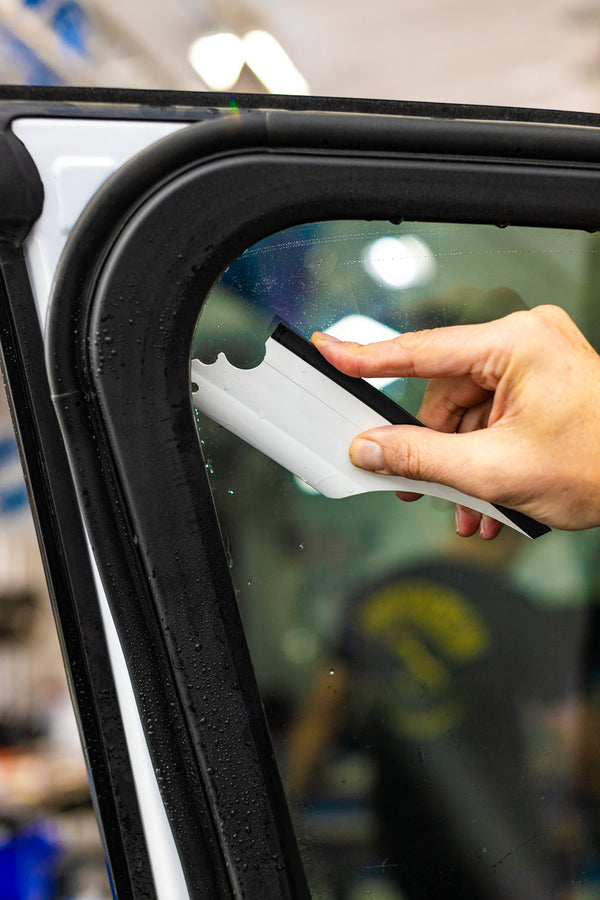 A person using a Yellotools YelloFlex Shape on a car window.