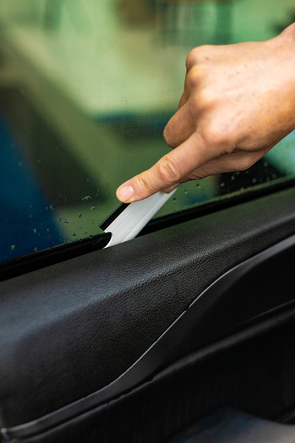 A person using a Yellotools YelloFlex Shape on a car window.