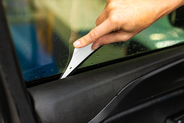 A person using a Yellotools YelloFlex Shape on a car window.
