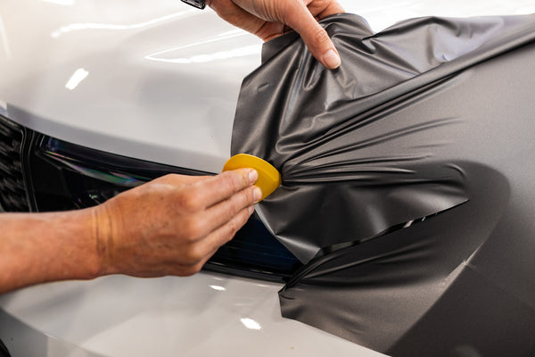 A person using the Yelloplek on a car headlight.