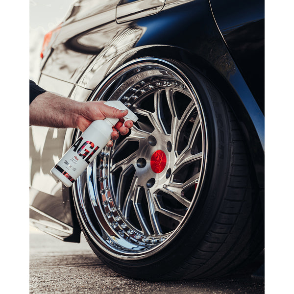 A closeup of a person spraying Stjarnagloss parla on a car tire rim.