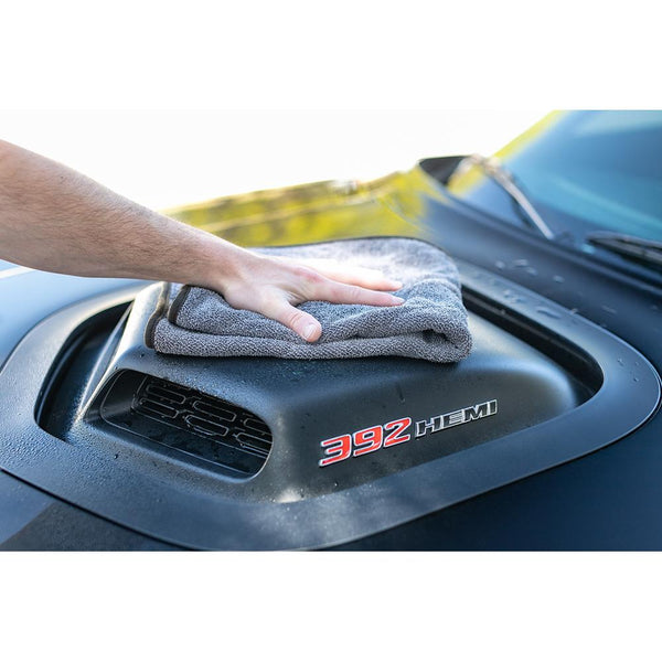 A closeup of a person wiping the hood of their black truck with a grey Double Twistress.