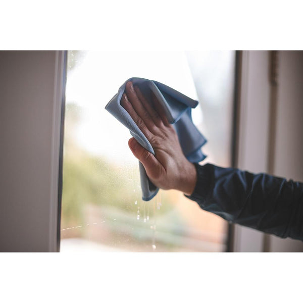 Using a blue Premium Glass & Window microfiber towel from The Rag Company to clean a window
