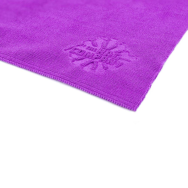 A close-up shot of the edgeless corner of a single Premium Pearl Edgeless towels from The Rag Company in a purple color. The Rag Company's logo is embossed on the corner of the towel