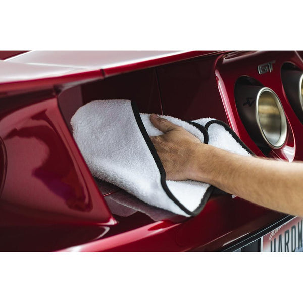 White microfiber towel being used to wipe down a red car