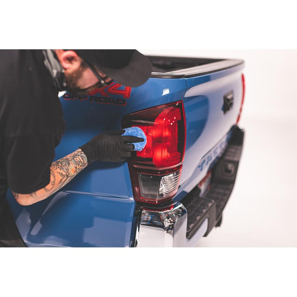 Using Gtechniq Crystal Serum Light (CSL) on a blue microfiber applicator sponge from The Rag Company to coat the tail lights of a blue Toyota Tacoma