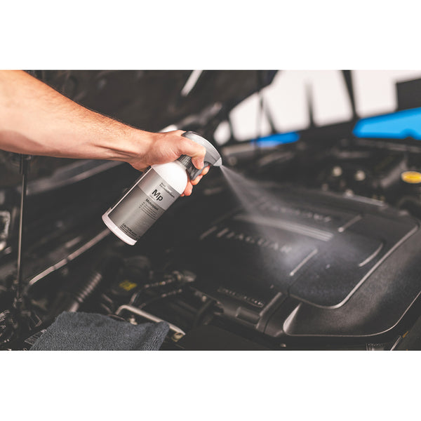 A closeup of a person spraying Koch Chemie Motor Plast on an engine.