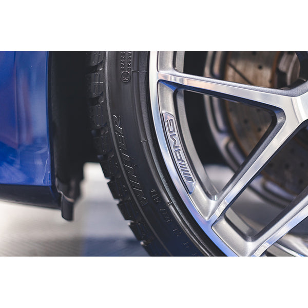 A closeup of a car tire on a blue car.