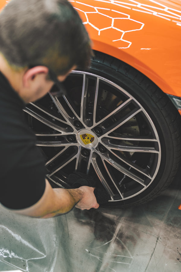 A closeup of a person cleaning a tire with a black towel.