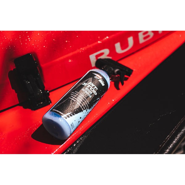 A spray bottle of P&S Pit Stop laying on the hood of a red jeep.