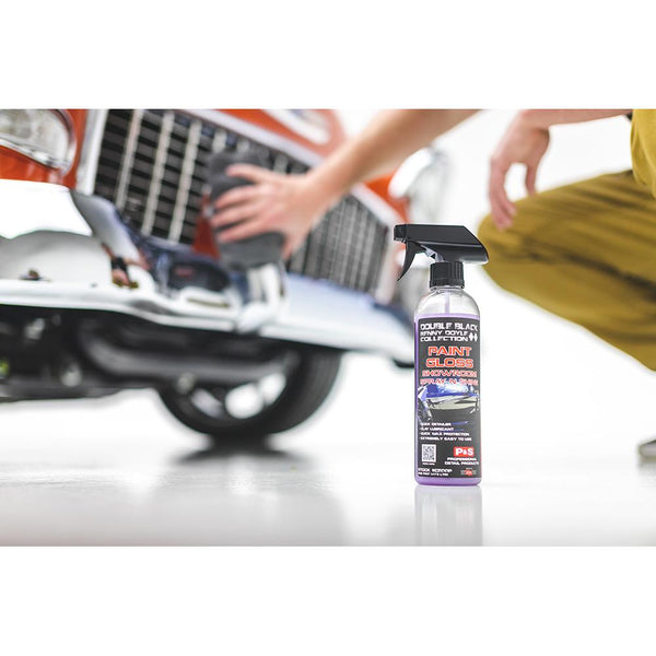 A spray bottle of P & S Paint Gloss with a person detailing a car in the background.