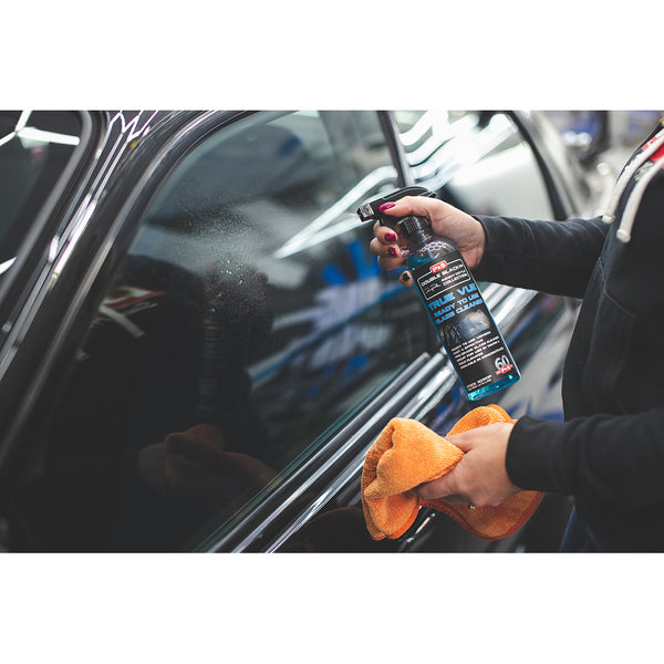 A closeup of a person spraying a car window with P & S True Vue while holding an orange towel.
