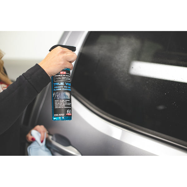 A closeup of a person spraying a car window with P & S True Vue.