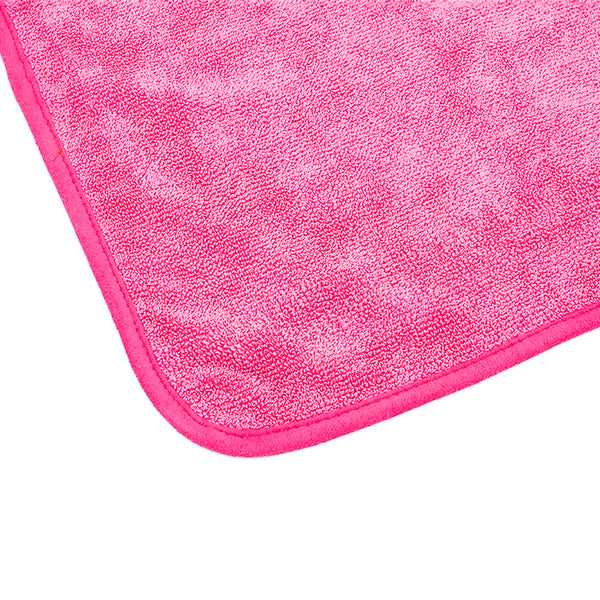 The corner of a pink Premium The Rag Company towel on a white background.