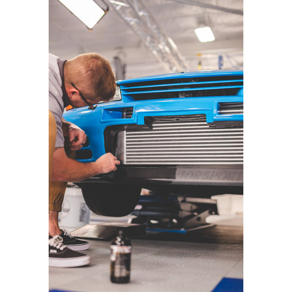 A person cleaning the grill of a blue car.