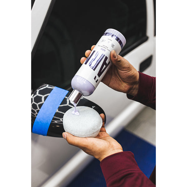 A person pouring Stjarnagloss Skara on a grey applicator in front of a white car.