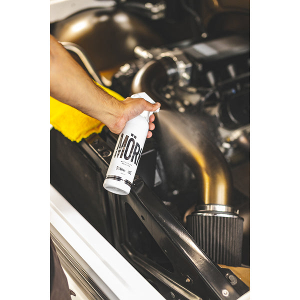A person spraying Stjarnagloss Mork Matte Finish Detailer onto an engine.
