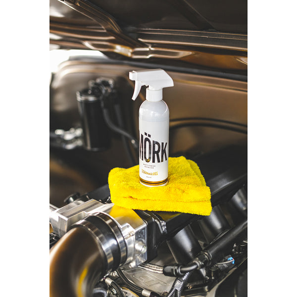 A spray bottle of Stjarnagloss Mork on a folded yellow towel on an engine.