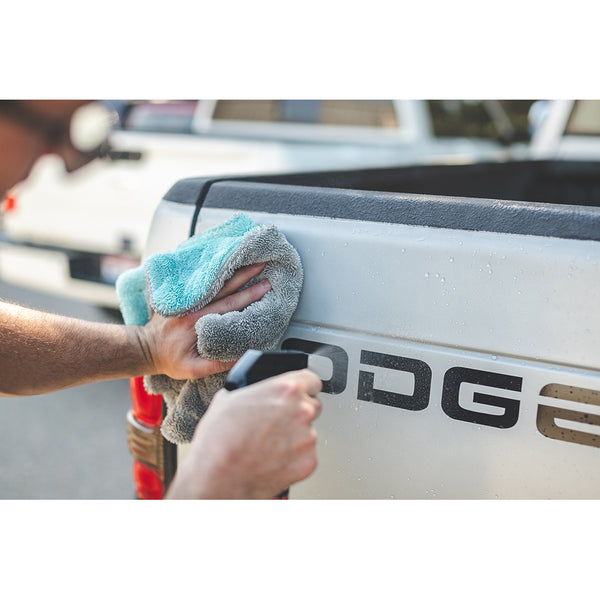 A closeup of someone spraying the Dodge emblem and wiping it with a liquid8 towel.