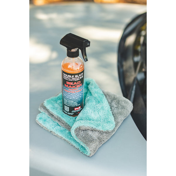 A spray bottle of P & S Bead Maker on a liquid8r towel on a white car hood.